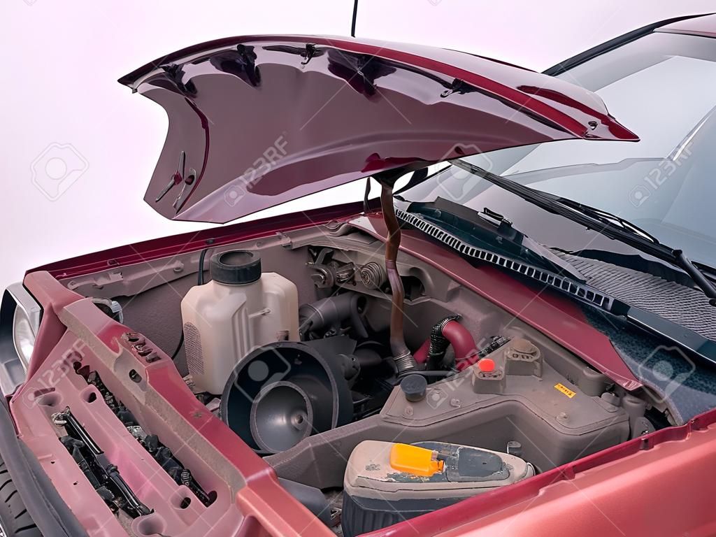 opened car hood with visible parts but without engine. mechanic fix, repair, service concept. side outdoor shot