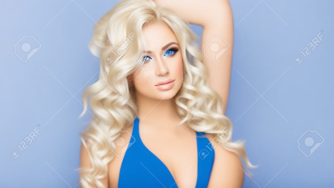 Schönheitsportrait der attraktiven zarte blonde Frau. Studio shot. Mädchen mit dem langen lockigen Haar und perfekt makeup.Blue Hintergrund.