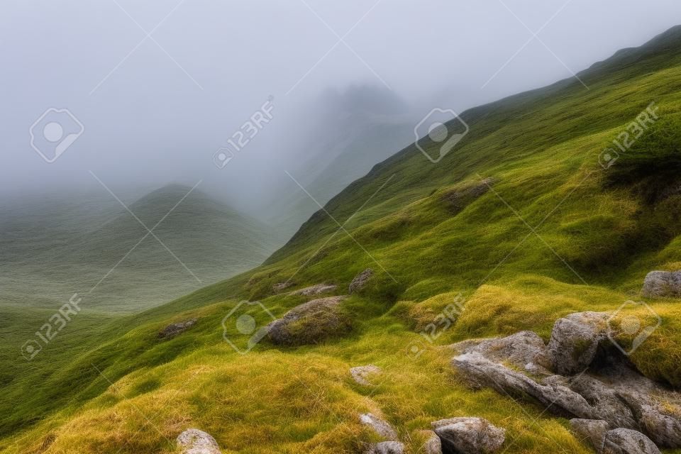 Bordo del ripido pendio sulla collina rocciosa nel tempo nebbioso. Scenario drammatico in montagna
