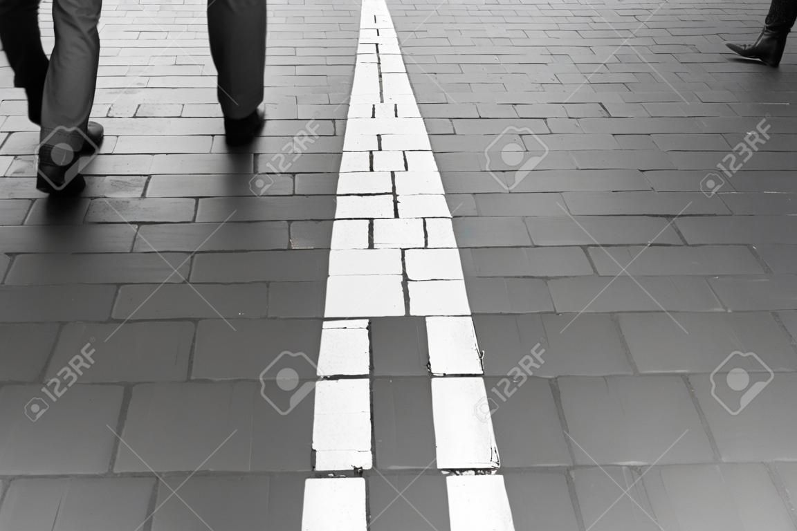Arrow straight on pavement walking street with walking people wear jeans fashion vintage black and white