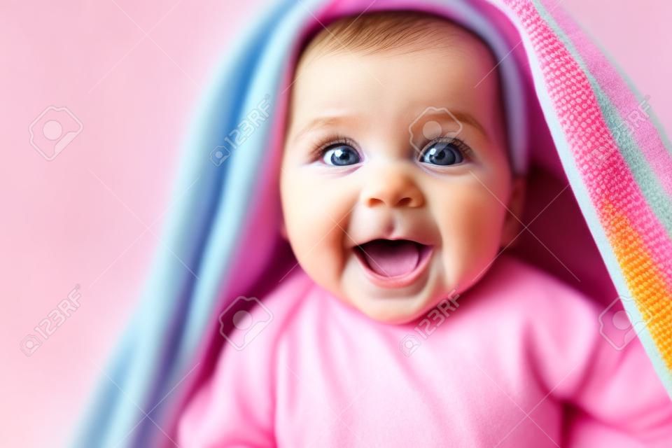 Baby's maken de wereld een leukere plek. schot van een schattige baby meisje bedekt met een kleurrijke deken thuis.