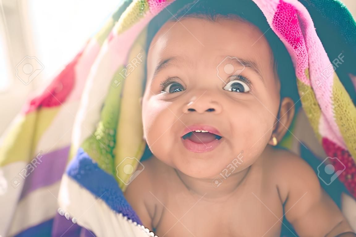 Os bebês fazem do mundo um lugar mais bonito. Tiro de uma menina adorável coberta por um cobertor colorido em casa.