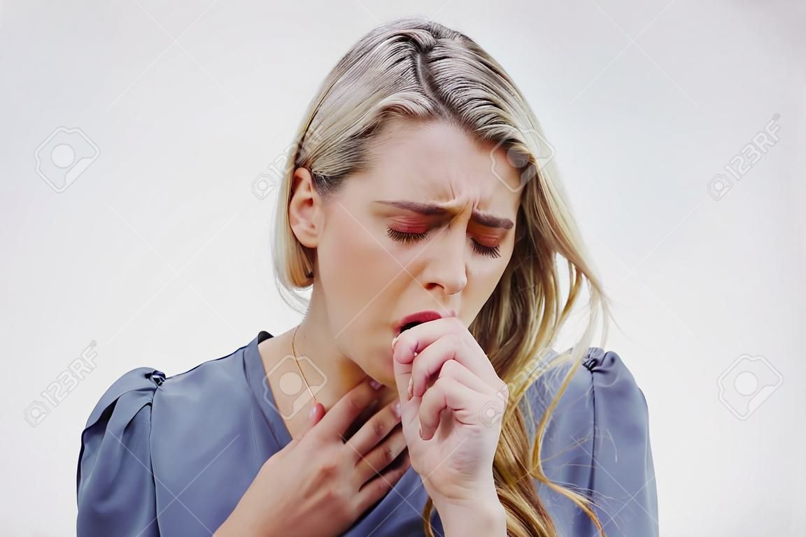 She hates being sick. Studio shot of an attractive young woman coughing against a grey background.