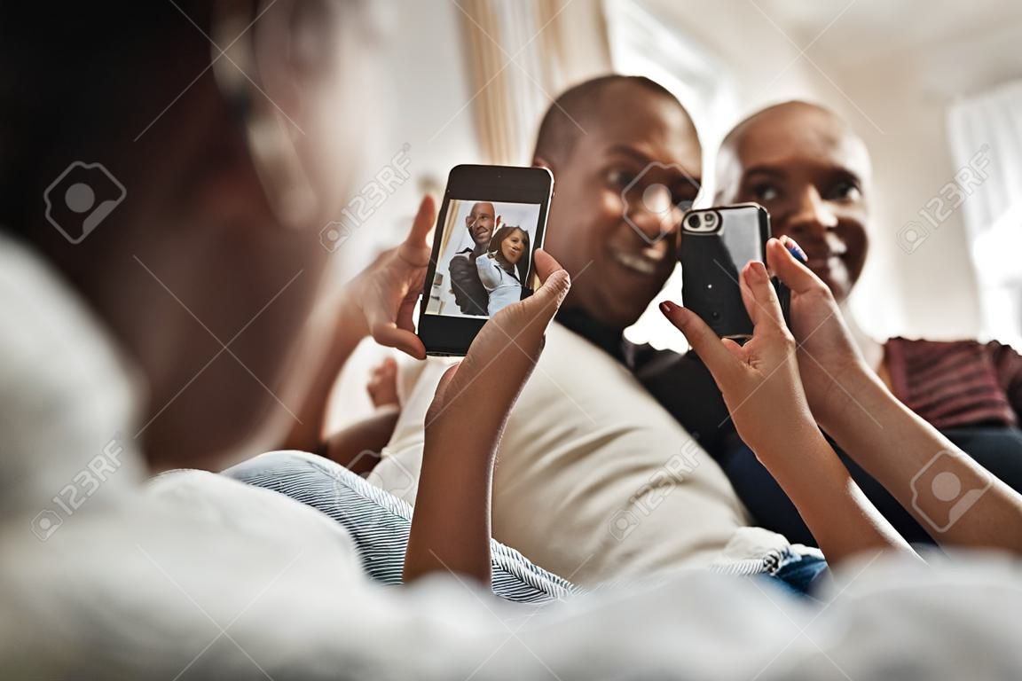 Shell geeft me altijd een reden om te glimlachen. Schot van een knappe jongeman poseren voor de camera terwijl zijn vriendinnen foto's van heme nemen met haar mobiele telefoon thuis.