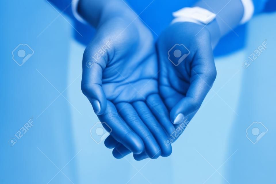 私は手を大きく開いてあなたの前に立ちます。青い背景に開いた手で手を差し伸べる認識できない人のクローズアップ。