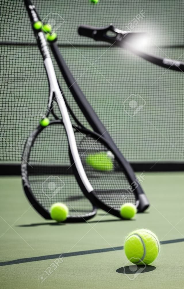 Groupe de balles de tennis et de raquettes contre un filet sur un terrain vide dans un club de sport pendant la journée. jouer au tennis est un exercice, favorise la santé, le bien-être et la forme physique. équipement et équipement après un match