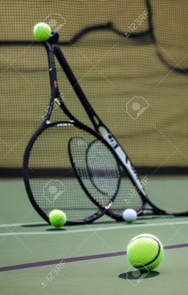 Groupe de balles de tennis et de raquettes contre un filet sur un terrain vide dans un club de sport pendant la journée. jouer au tennis est un exercice, favorise la santé, le bien-être et la forme physique. équipement et équipement après un match