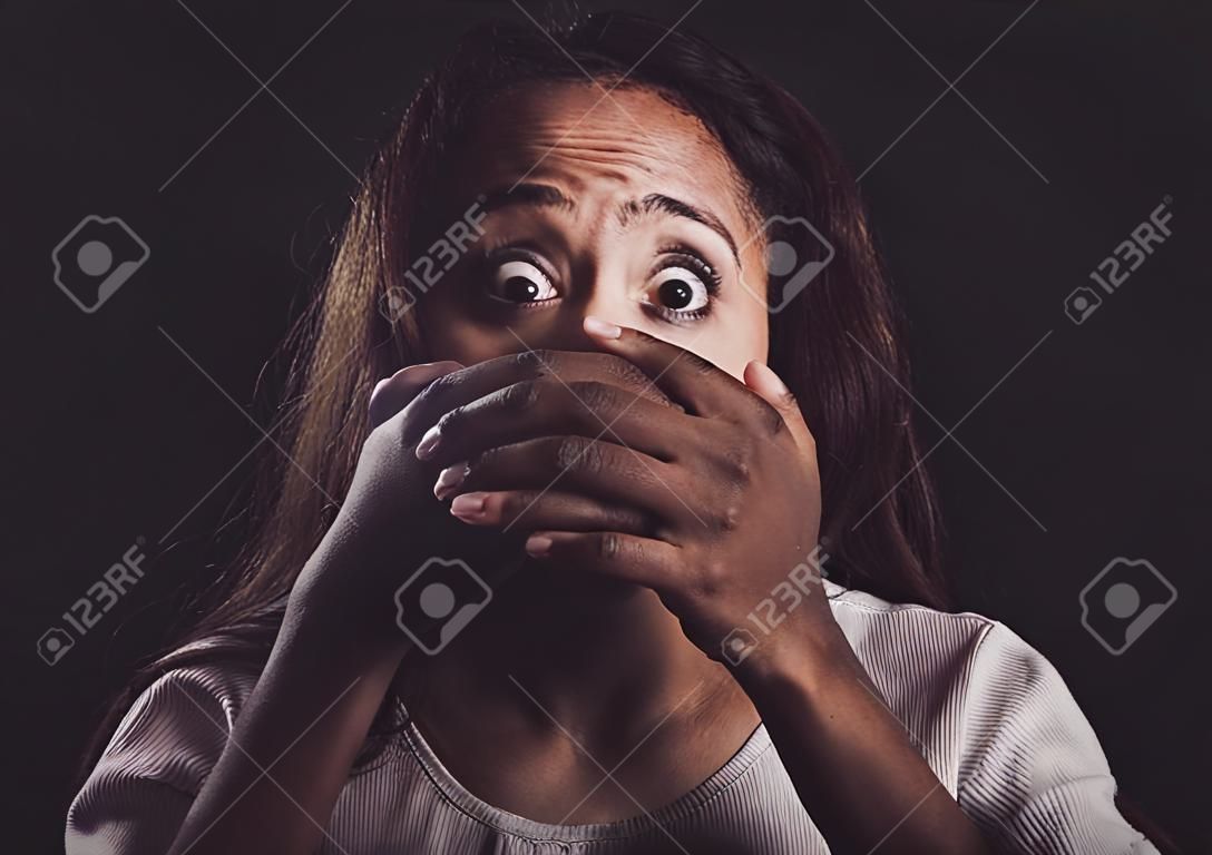 You wake up every morning to fight the same demons. Shot of a scared young womans mouth being covered by an unrecognisable mans hand against a black background.