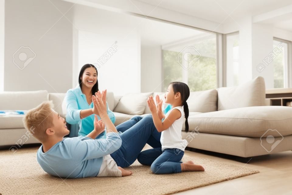 Faites en sorte que chaque moment passé ensemble compte. une famille heureuse de trois personnes jouant ensemble à un jeu d'applaudissements à la maison.