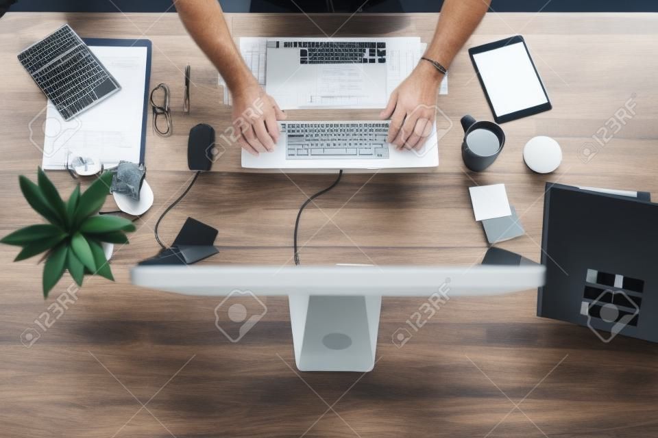 Stanowisko pracy, na którym wszystko się dzieje. Ujęcie biznesmena korzystającego z komputera przy biurku w nowoczesnym biurze pod dużym kątem