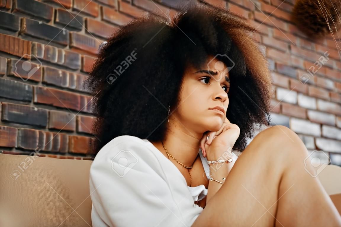 Femme fatiguée, déprimée et triste pensant au divorce, à la dépression et au stress anxieux avec un problème de santé mentale sur le canapé à la maison. fille africaine souffrant d'épuisement professionnel, traumatisée par la maltraitance et frustrée par une erreur