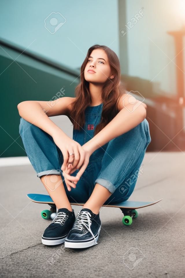 Hipster skateboard girl, relax on street of city and thinking of a future cool skateboarding skate park. Young urban woman, creative casual fashion and trendy gen z teen sitting in California sun