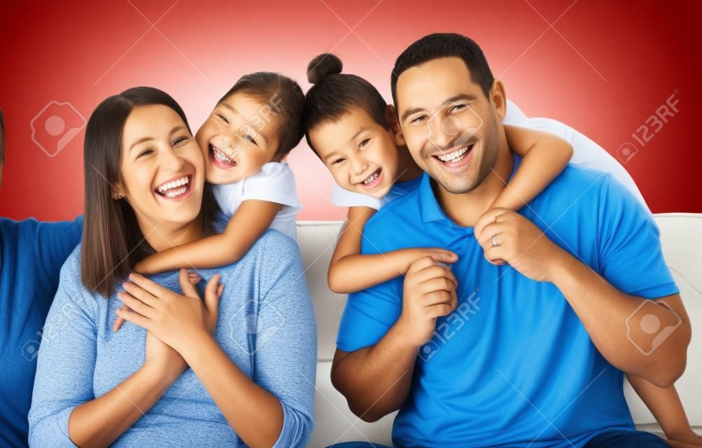 Happy family, mother and father with children in a portrait in a sofa bonding hugging and laughing together. Mom, dad and fun Mexican kids playing, kissing parents and enjoying quality time in Mexico