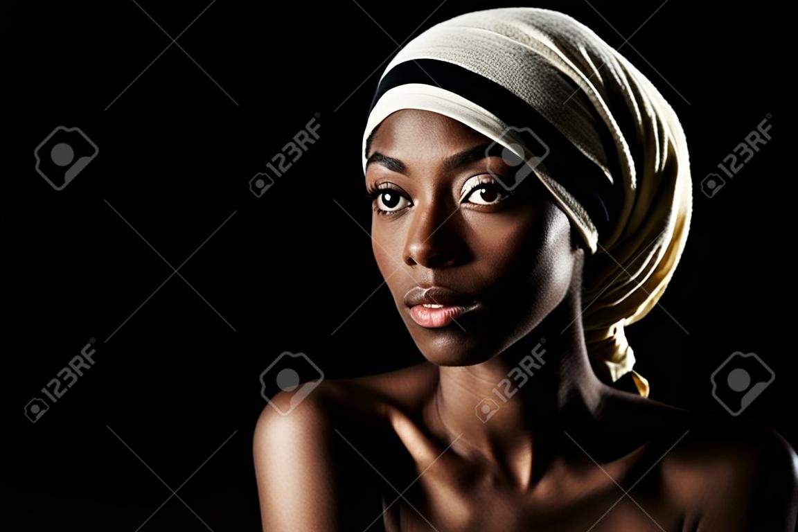 Envolvido em estilo. Foto de estúdio de uma bela mulher usando um lenço de cabeça contra um fundo preto.