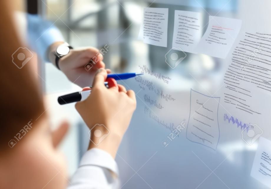 Marquer leurs idées au fur et à mesure. gros plan de deux femmes d'affaires remue-méninges avec des notes sur un mur de verre dans un bureau.