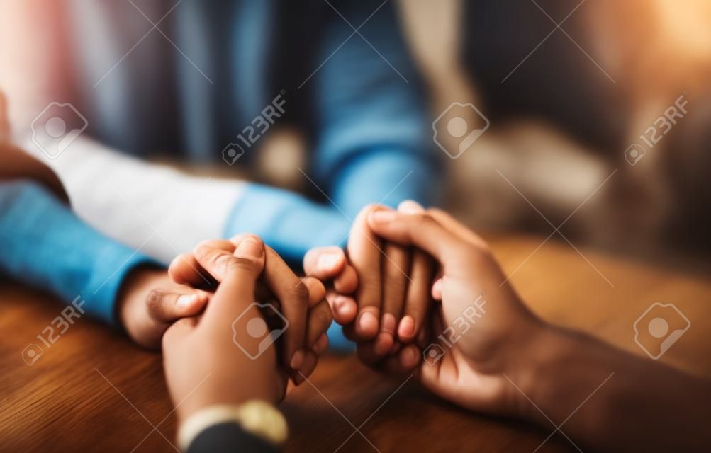 Samen kunnen we alles overwinnen wat op onze weg gegooid wordt. Close-up shot van twee onherkenbare mensen die handen vasthouden in comfort thuis.