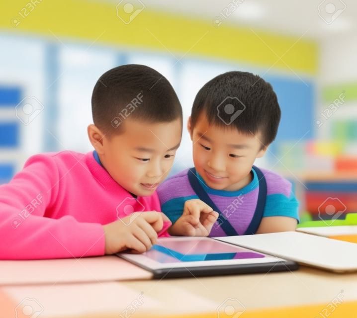 Did you see this. two elementary school children browsing on a digital tablet inside of the class during the day.