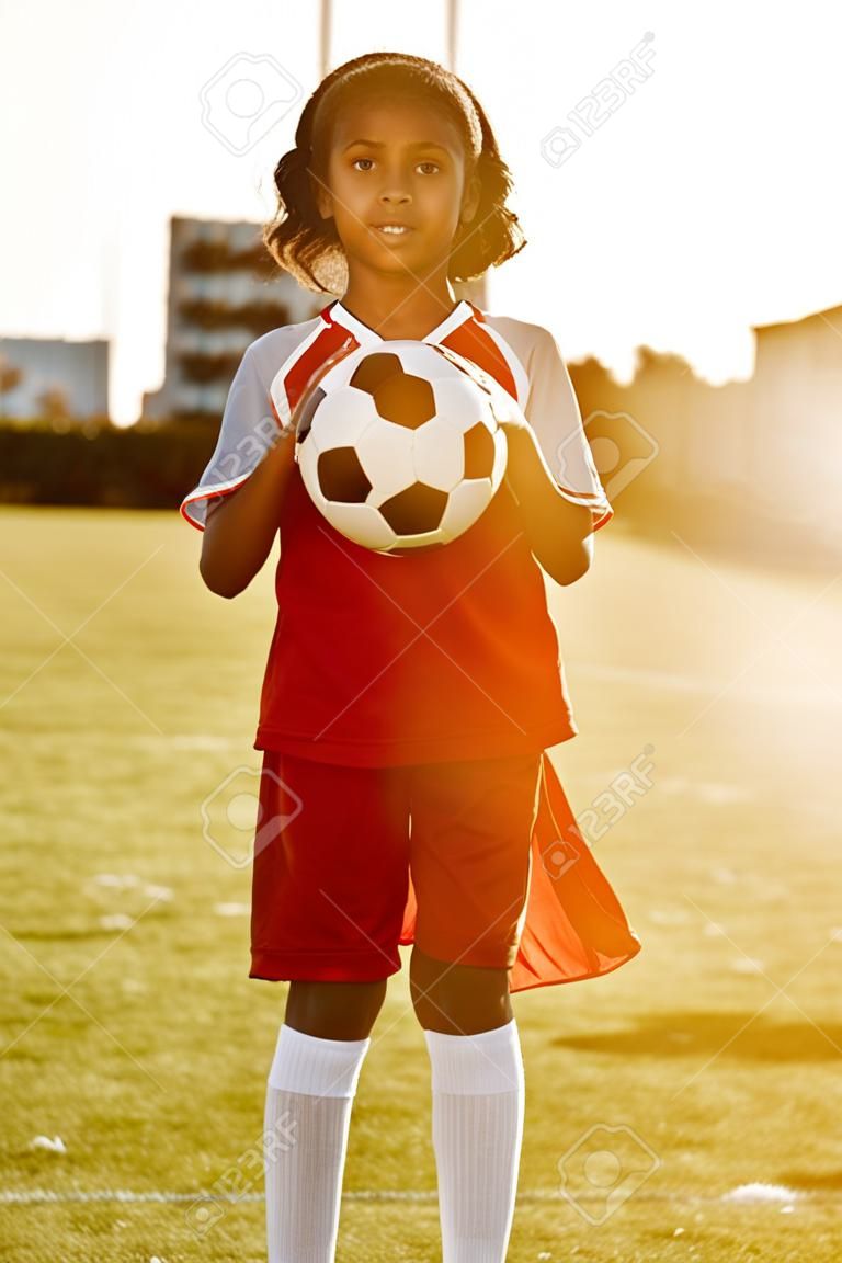 Futbolista, retrato y jugadora de fútbol en un campo deportivo listo para un partido de pelota o un partido de entrenamiento al aire libre. sonrisa, fitness y niño emocionado por practicar entrenamiento en campo de hierba en sao paulo