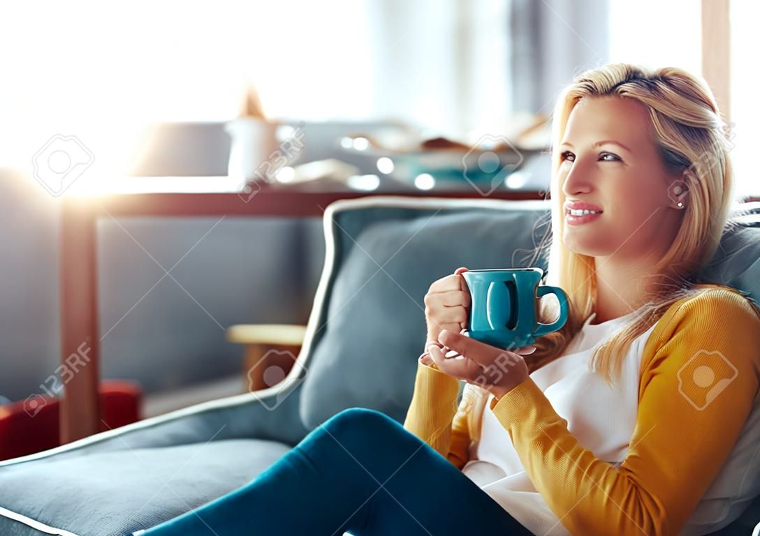 Having coffee in my favorite cup. a young woman relaxing on her sofa with a cup of coffee.