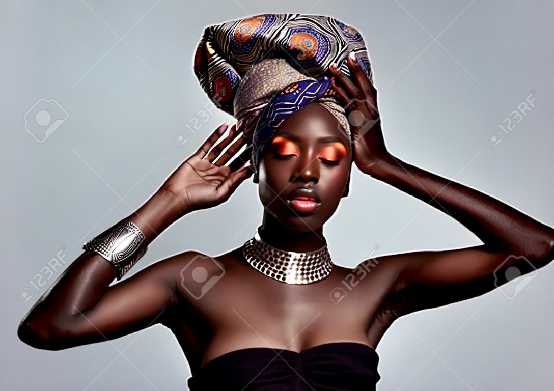 Maquillage de mode africaine et femme noire en studio sur fond blanc avec des cosmétiques de luxe et du luxe glamour de beauté et le visage d'une personne féminine brille dans un style traditionnel de bijoux exotiques et une écharpe