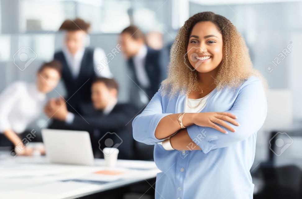 Positivity and confidence. Cropped portrait of an attractive young businesswoman standing with her arms folded with her colleagues in the background.