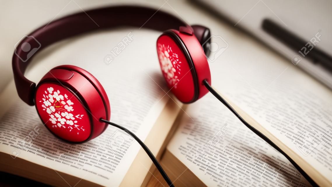 Morgenentspannung und -cosy mit rotem Herzen und kleine Blumen auf dem Buch mit Kopienraum auf hölzernem Hintergrund für Nostalgiker, Lebensstil, Musiktherapiekonzept