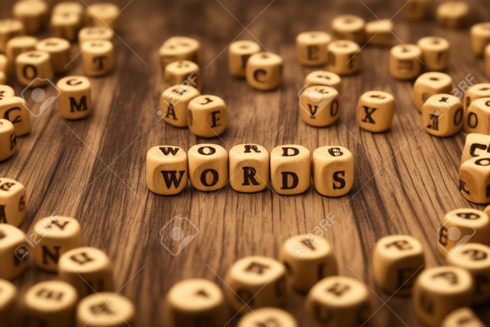 Palavra feita com letra de madeira de bloco ao lado de uma pilha de outras letras sobre a composição da superfície da placa de madeira. Bloco ABC.