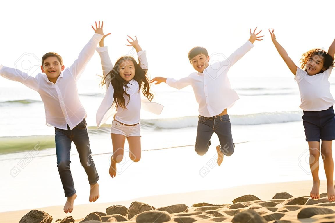 Niños felices saltando junto con la luz del sol en la playa