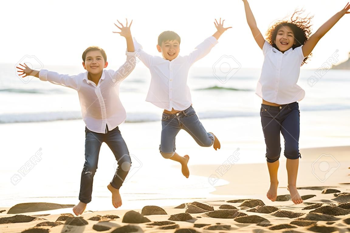 Niños felices saltando junto con la luz del sol en la playa