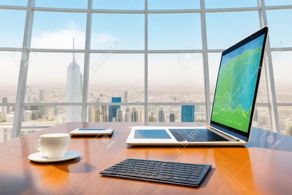Soleggiato ufficio con vista megalopoli della città, tavoletta digitale e schermo del computer portatile con il diagramma di affari sul tavolo di legno