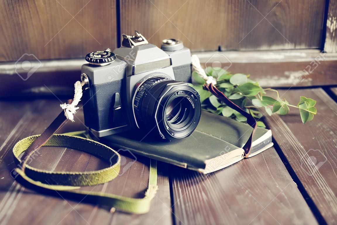 Vecchia macchina fotografica di stile con il vecchio diario sul tavolo in legno
