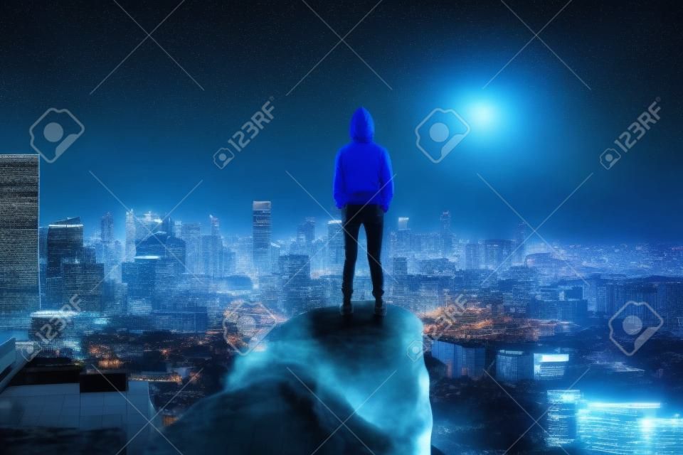 back view on hacker in hoody on top of the rock above night megapolis city