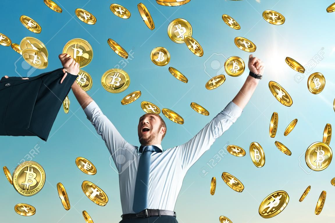 Uomo d'affari che celebra la pioggia bitcoin dorata sullo sfondo del cielo. Criptovaluta e concetto di successo