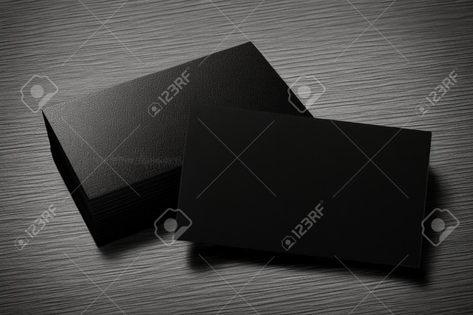 Empty black business card stack on concrete desk. Info, address and message concept. Mock up, 3D Rendering