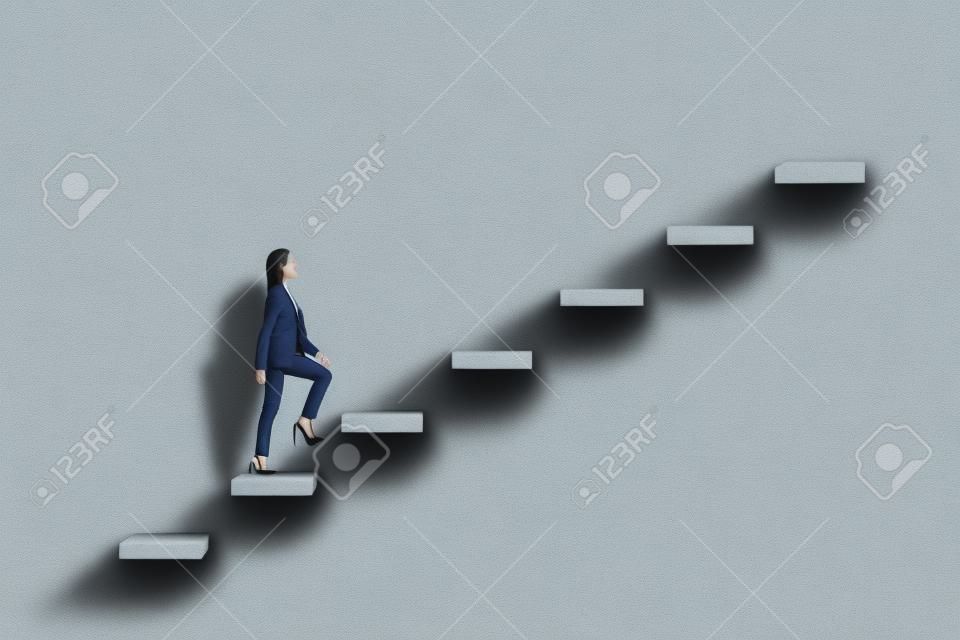 Seitenansicht der jungen Geschäftsfrau, die Treppe zum Erfolg auf Betonmauerhintergrund klettert. Führungs- und Karriereentwicklungskonzept