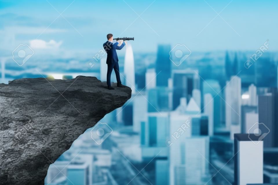 Attractive young european male with telescope on cliff edge looking into the distance on bright city background with daylight and mock up place. Future, success, leadership and career growth concept