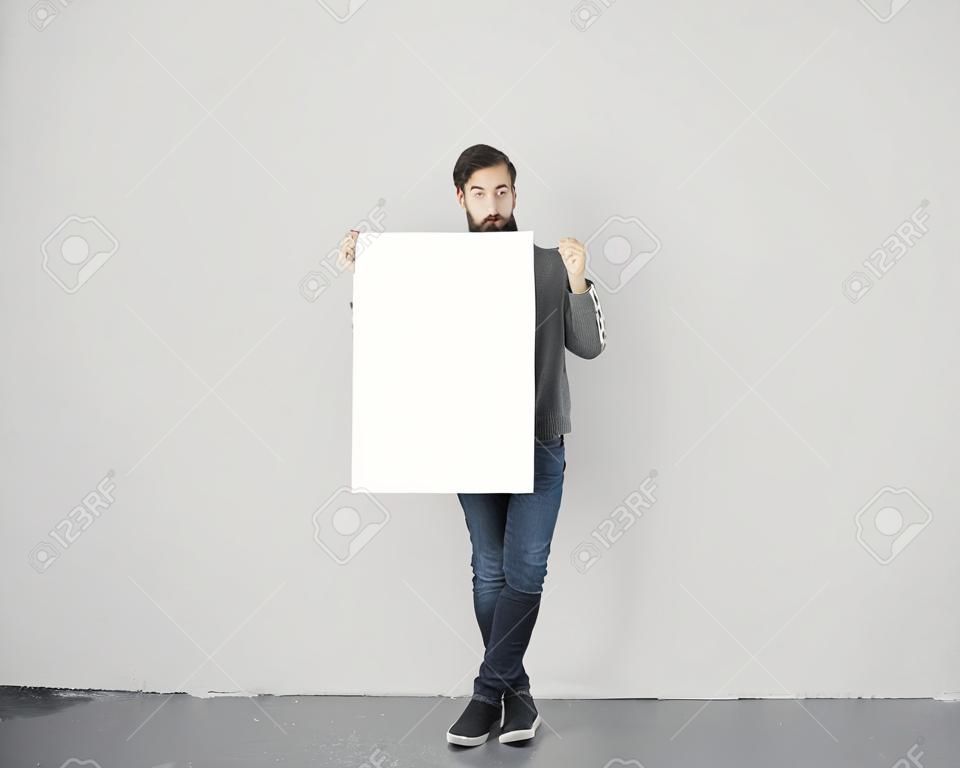 young hipster holding blank poster