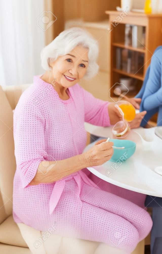 Attractive elderly woman eating breakfast.