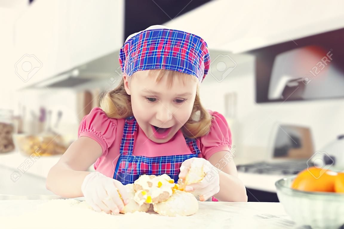 Schattig klein meisje in schort bakken koekjes thuis keuken