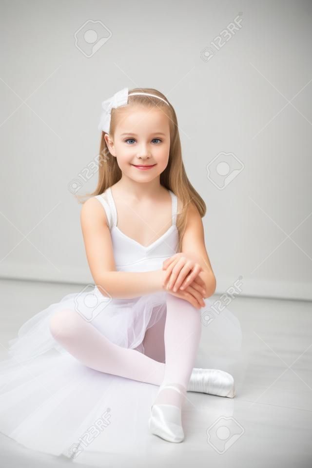 Довольно прилежным балет девушка сидит в белой пачке в одиночку танцевальной студии