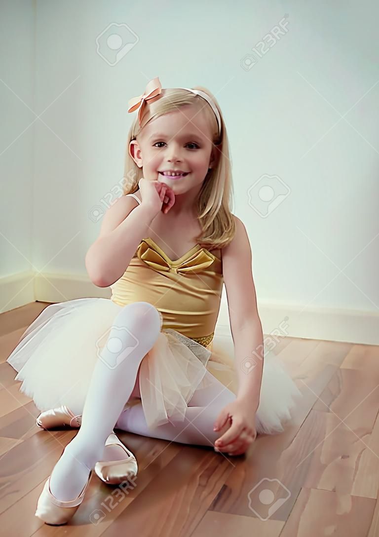 Carina bimba bionda seduta in tutù di balletto con un fiocco tra i capelli