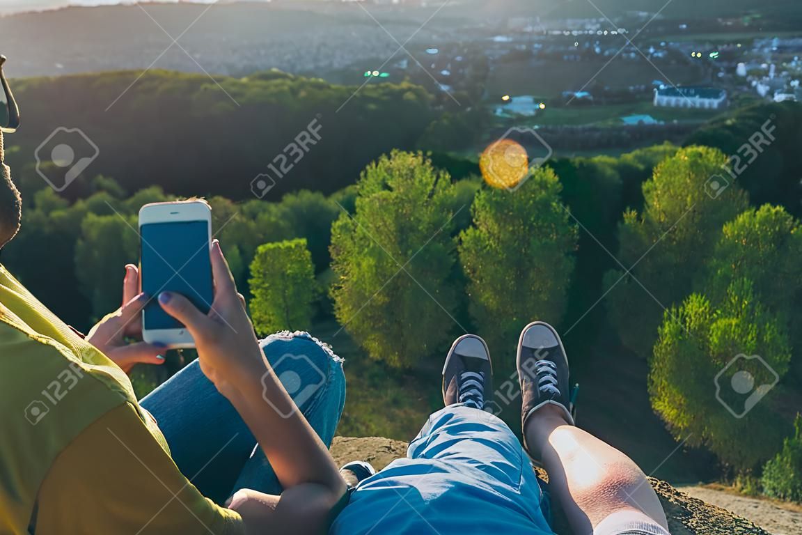 женщина с мужчиной сидят на вершине холма и наслаждаются видом на закат