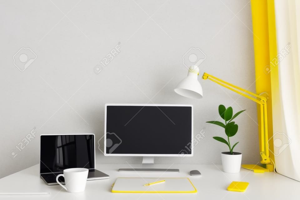 lugar de trabajo. escritorio blanco con laptop y taza amarilla. lugar de trabajo del diseñador