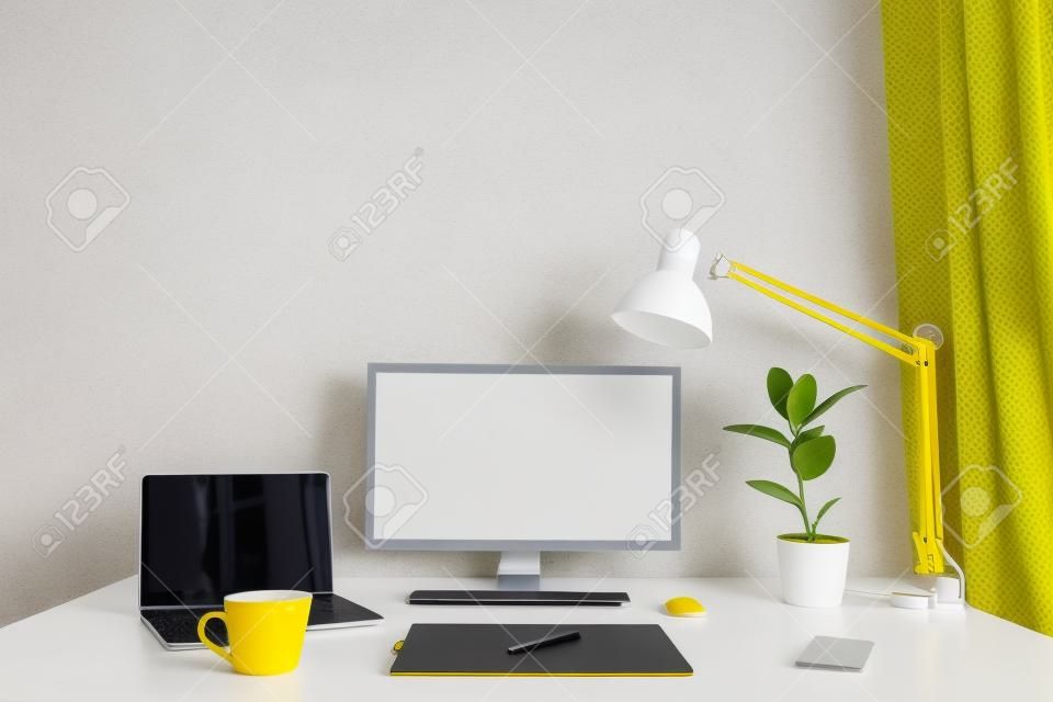 lugar de trabajo. escritorio blanco con laptop y taza amarilla. lugar de trabajo del diseñador