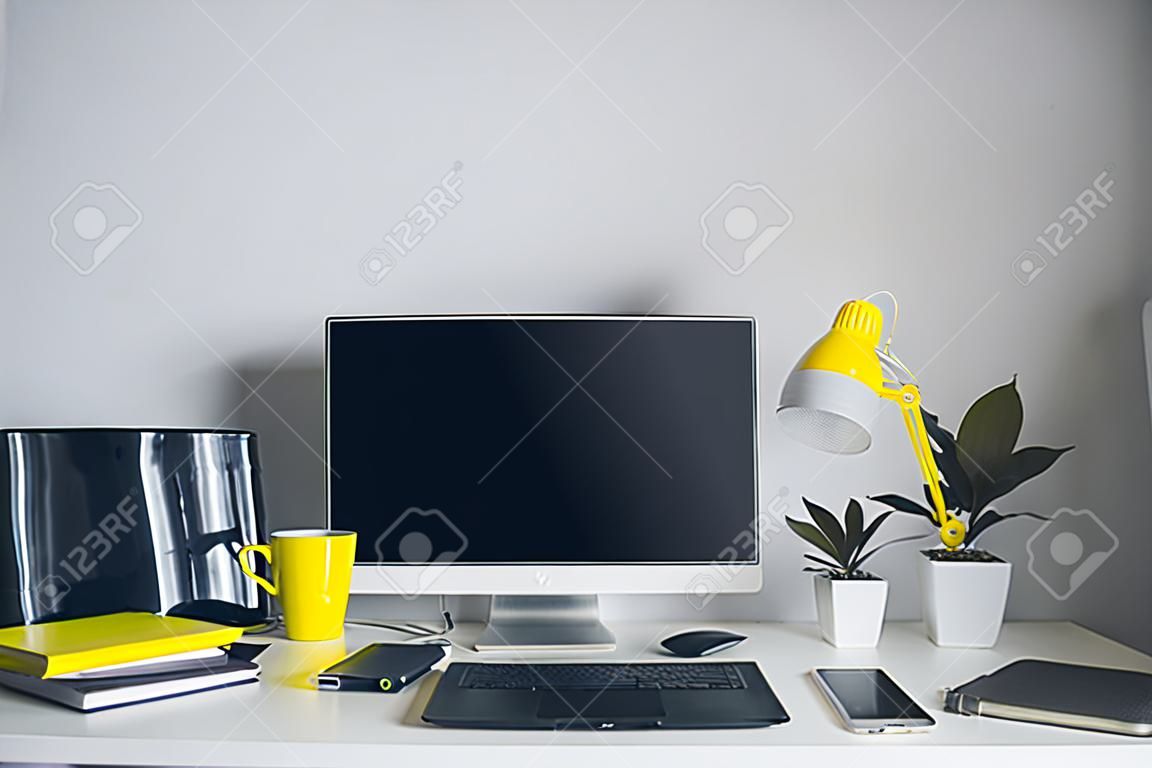 workplace. white desk with laptop and yellow cup. designer working place