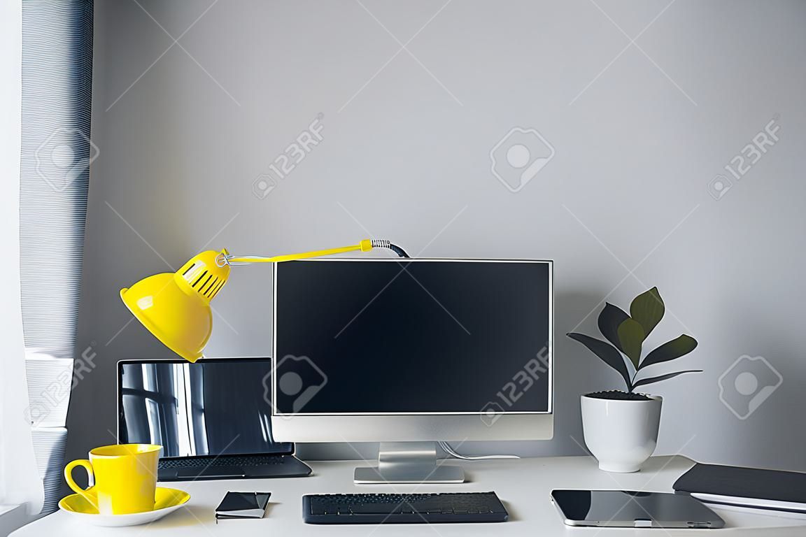 직장. 노트북과 노란색 컵이 있는 흰색 책상. 디자이너 작업 공간