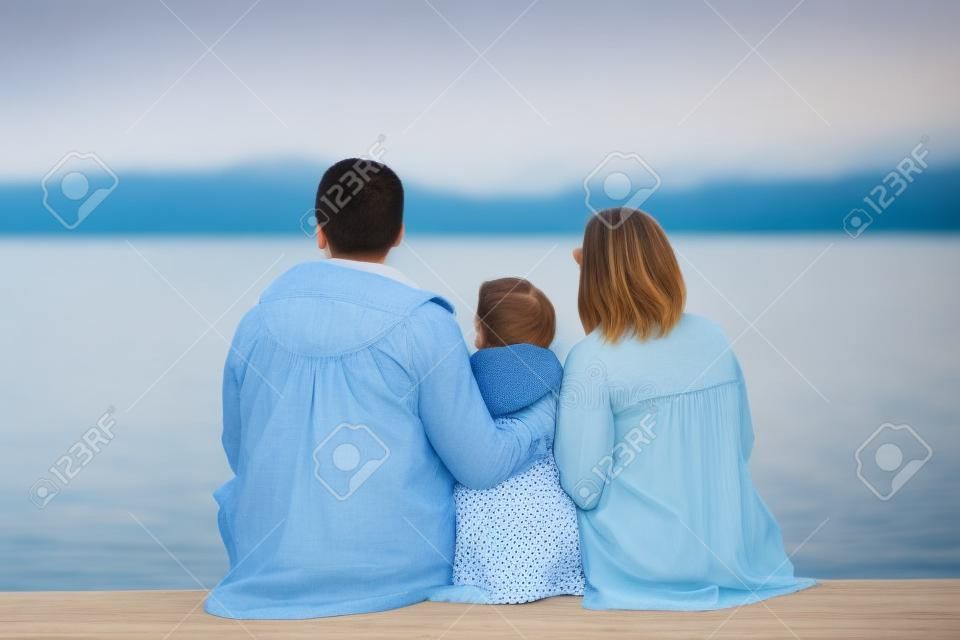 young beautiful family sitting at beach with view lake
