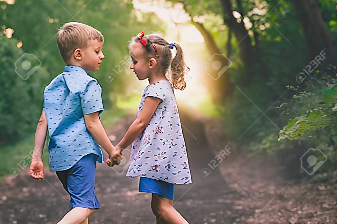 I bambini felici che camminano all'aperto al parco si tengono per mano.