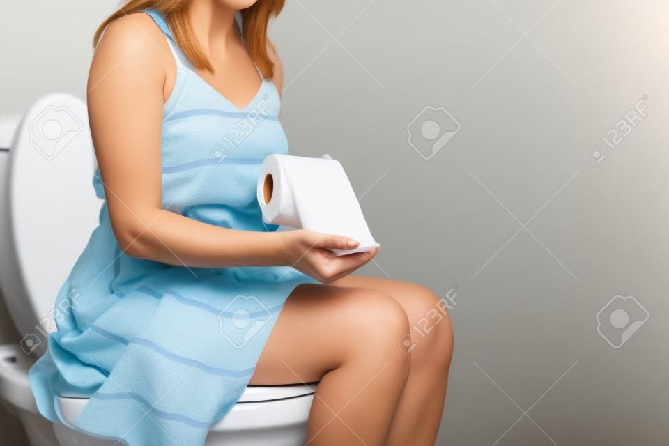 Woman sitting on toilet with toilet paper concept.
