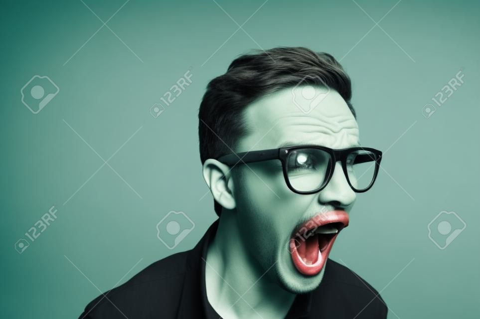 在灰色背景下用绿色眼镜尖叫的男人